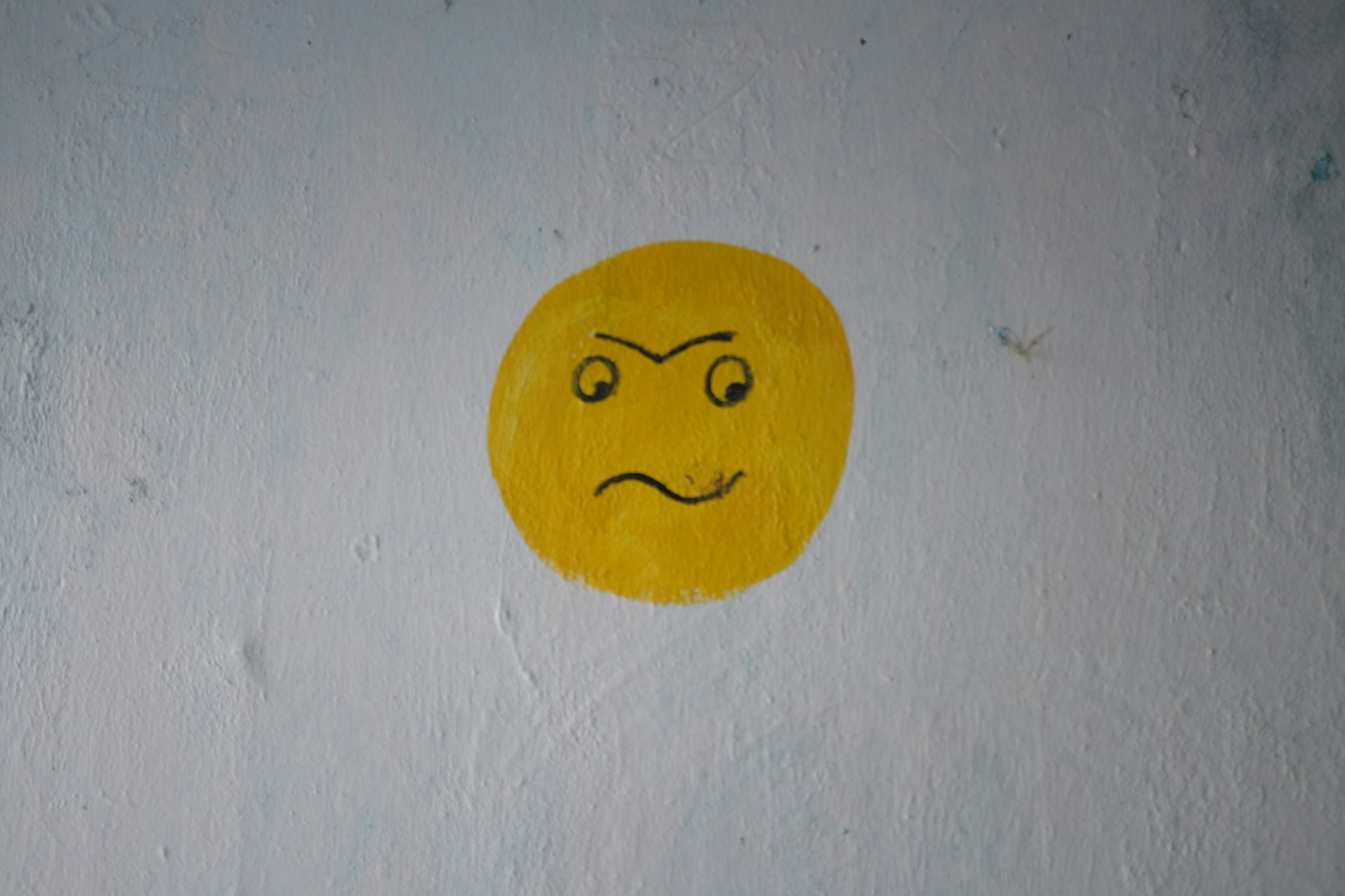 a yellow smiley face painted on a white wall